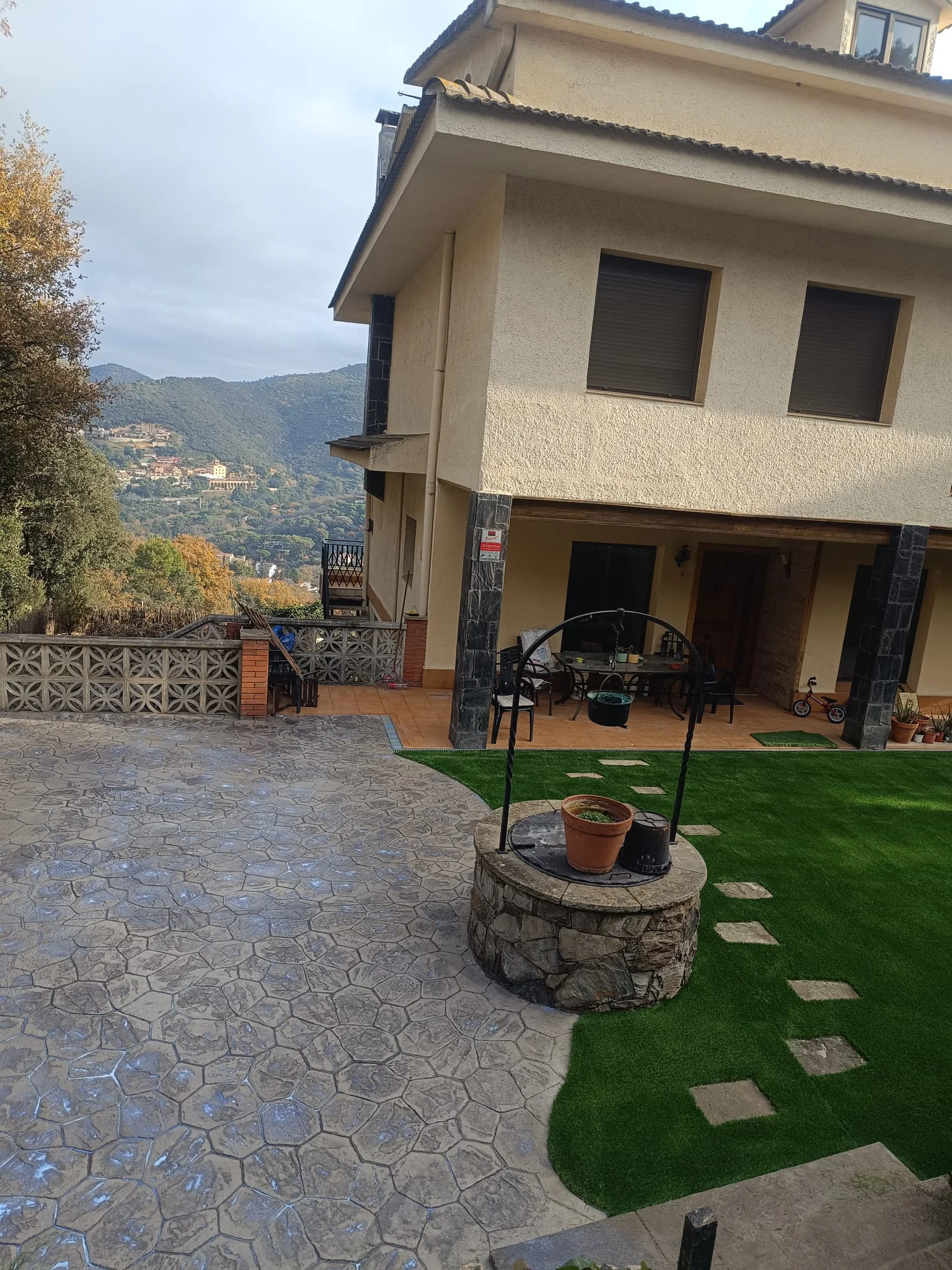 Jardín con césped artificial y pavimento decorativo en vivienda