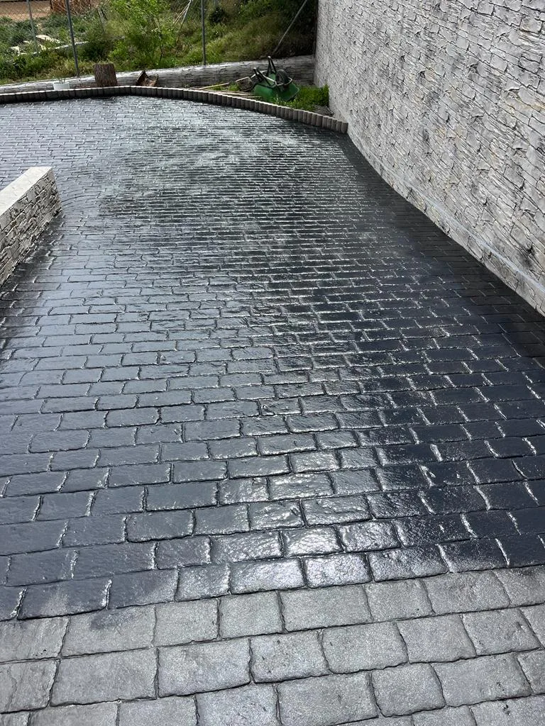 Hormigón impreso gris oscuro sellado en patio exterior con acabado protector